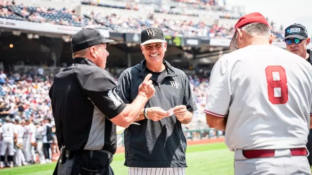 Tom Walter smiling at home plate beside an umpire and an opposing coach